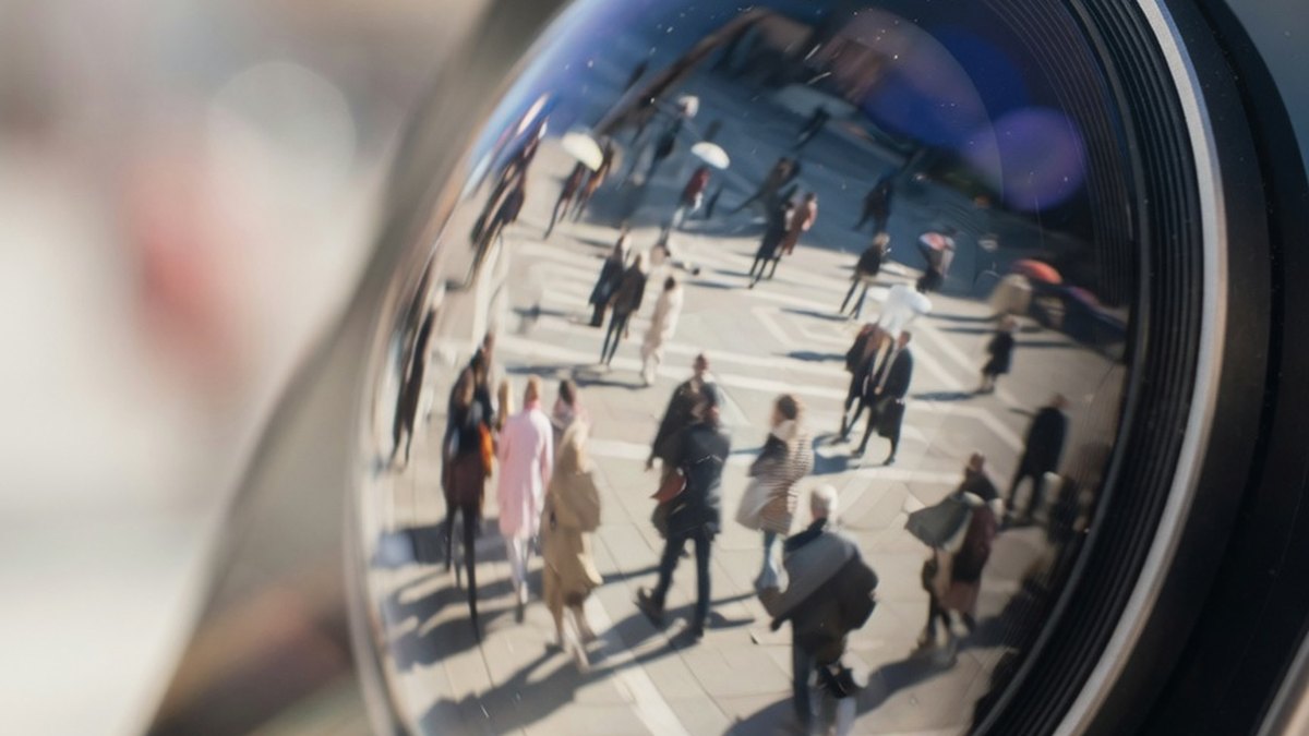 Gros plan sur un smartphone filmant une foule floutée sur une place publique, illustrant la différence entre capter et diffuser une image