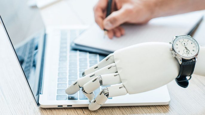 Une main robotisée tape sur un clavier d'ordinateur