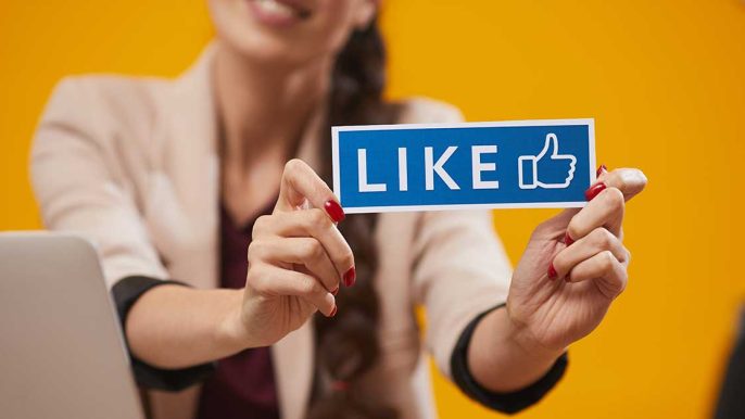 Femme travaillant en agence de communication avec un panneau like de facebook le réseaux social