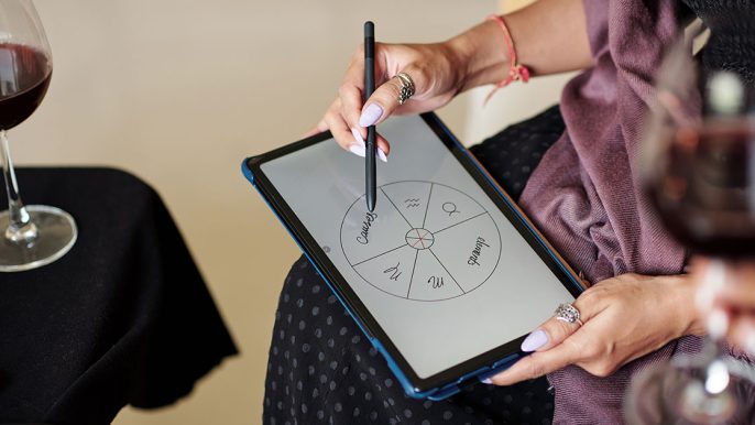 Image en gros plan d'une astrologue féminine dessinant une carte natale pour un client sur une tablette
